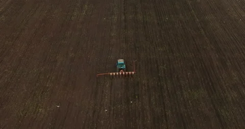 Tractor is plowing land and seeding cereals crops, view from drone of Stock Footage 197692928