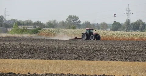Tractor is Plowing The Soil Field Plants Bushes Straw High-Voltage Wires Tower Stock Footage 53608080