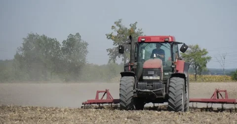 Tractor is Plowing The Soil With Plow Flying Dust Field Trees on a Horizon Stock Footage 53607645