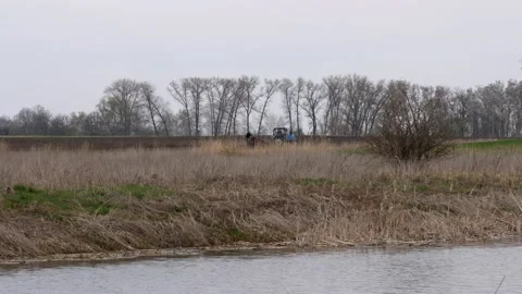 Tractor plows the field against the background of the river. Stock Footage 184611930