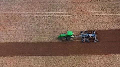 Tractor plows field, harrows soil. Preparation for planting new crop, drone view Stock Footage 245992759