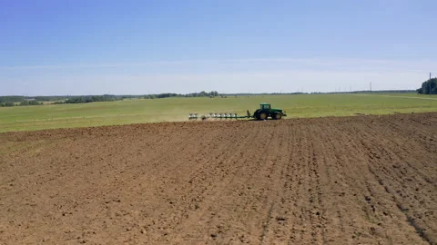 Tractor plows the field by plow, plowing fields. Farmer preparing the soil for Видео 144058136