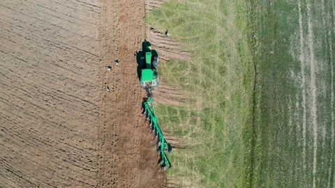 Tractor plows the field by plow, plowing fields. Farmer preparing the soil for Video stock 144058690