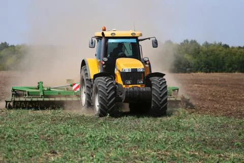 Tractor plows the field in the spring. Front view Stock Photos