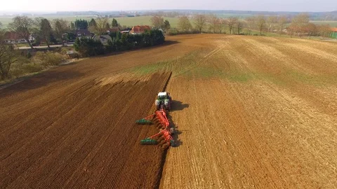 Tractor plows a field in spring -Tractor cultivating a field  - Aerial view Stock Footage 88500635