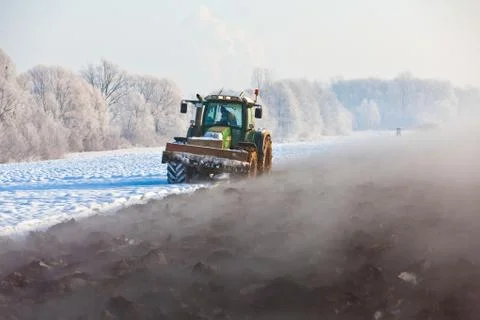 Tractor plows field in winter Stock Photos