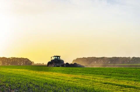 Tractor plows the ground in the spring in the field before planting grain Stock Photos