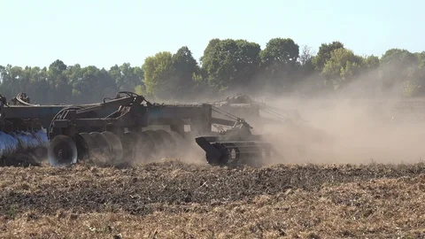 Tractor plows seeder with dry black soil, sows wheat on large agricultural Stock Footage 117264173