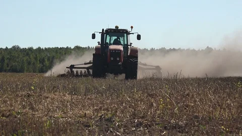 Tractor plows seeder with dry black soil, sows wheat on large agricultural Stock Footage 117364984