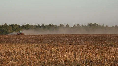 Tractor plows the seeder with dry black soil, sows wheat on a large agricultural Stock Footage 122005983