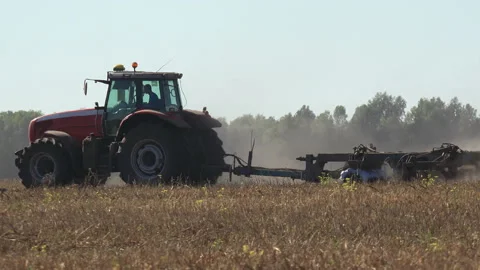 Tractor plows the seeder with dry black soil, sows wheat on large agricultural Stock Footage 154549319