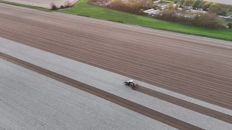 Tractor prepares broad agricultural field with parallel soil rows in the Po Stock Footage 344476152