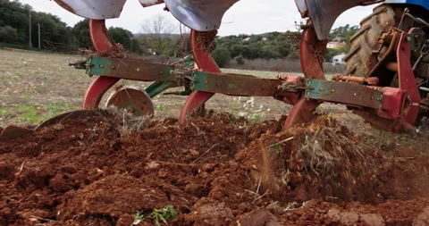 Tractor preparing soil in a field for planting crops in rural setting Stock Footage 321356580