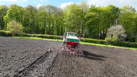 Tractor Pulling Agricultural Equipment Across Field Stock Footage 323938080