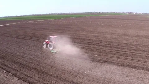 Tractor pulling land cultivating machine for sowing preparation. Aerial footage. Stock Footage 80045238