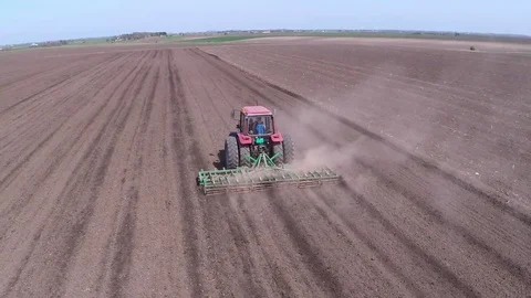 Tractor pulling land cultivating machine for sowing preparation. Aerial footage. Stock Footage 80045686