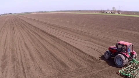 Tractor pulling land cultivating machine for sowing preparation. Aerial footage. Stock Footage 80045985