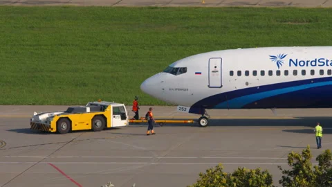 Tractor pulling passenger plane, side view Stock Footage 304991118