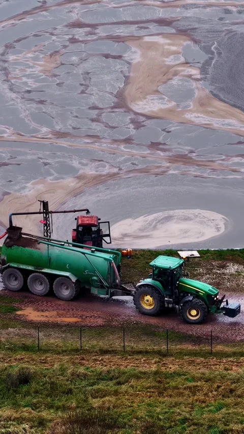 Tractor pulling a Samson slurry tanker in a muddy field. Video stock 336728482