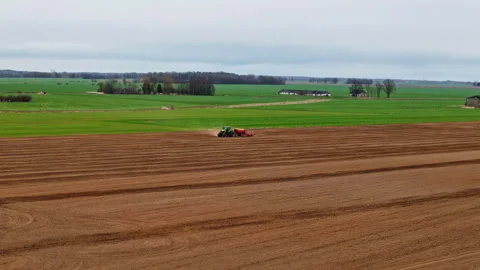 Tractor pulling seeder on cultivated field in spring season Stock Footage 308766947
