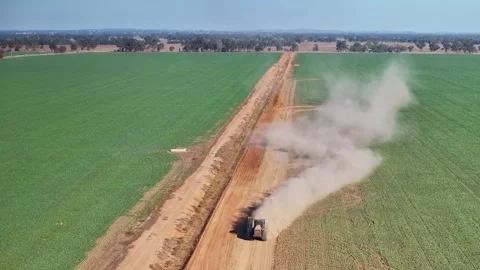 Tractor pulling small road grader causes dust to billow over the crop Stock Footage 276971388