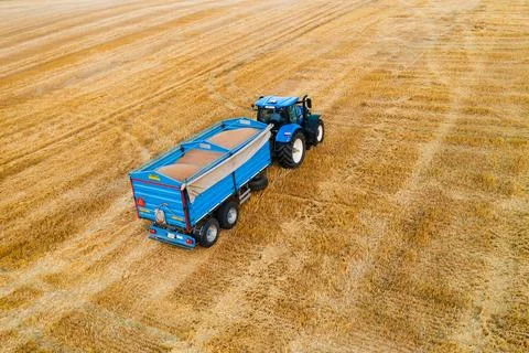 Tractor Pulling Trailer Across Field, Agricultural Work in Progress Stock Photos