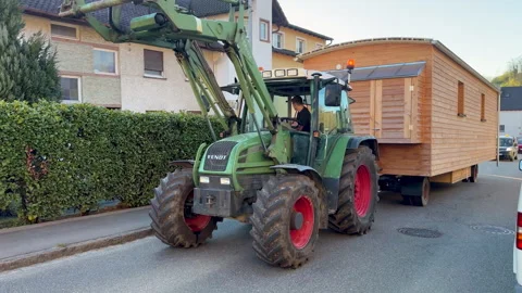 A tractor pulling a trailer with a wooden house on it Video stock 336099025