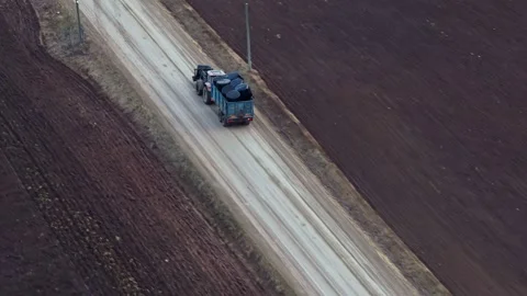 Tractor pulling a trailer with wrapped hay bales on a farm road, moving harvest Video stock 333869917
