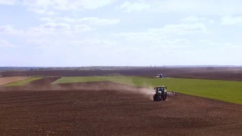 The tractor pulls the harrow and raises the dust. Soil cultivation in the field Stock Footage 89136205
