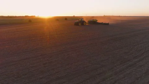 A tractor pulls a planter through a field in sunset aerial view in Kansas USA Vídeo Stock 169762041
