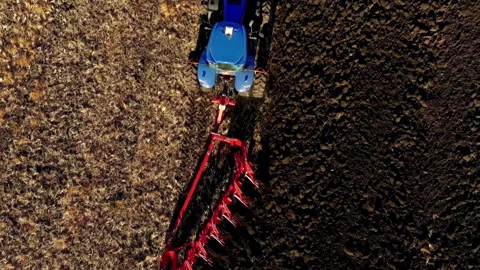 A tractor pulls a plough in the field, cutting through the hard black soil. Stock Footage 285235675