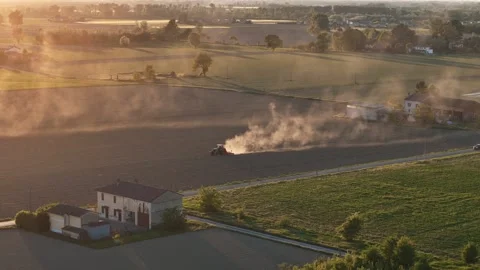 Tractor raising dust beside Strada Padana Inferiore in Po Valley Italy sunset Stock Footage 335968473