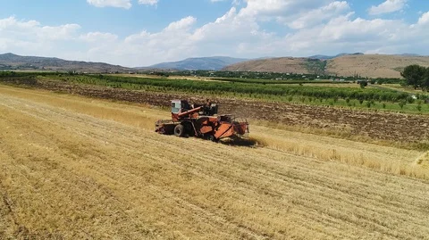 Tractor reaping, collecting and compressing wheat Stock Footage 129711697