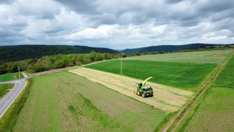 The tractor removes the grass in the field by the road Stock Footage 154514820