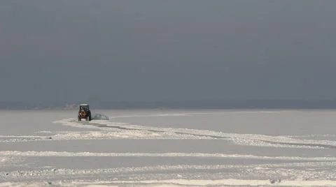 Tractor removing snow from the winter road on the frozen sea Stock Footage 62728334
