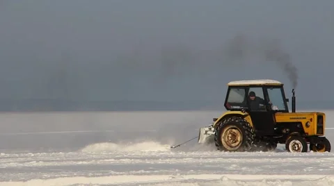 Tractor removing snow from the winter road on the frozen sea Stock Footage 62728566