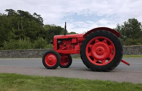 Tractor on the road in red. Stock Photos