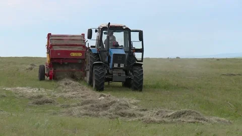 Tractor with roller press baler collects the grass in the field Stock Footage 132737372