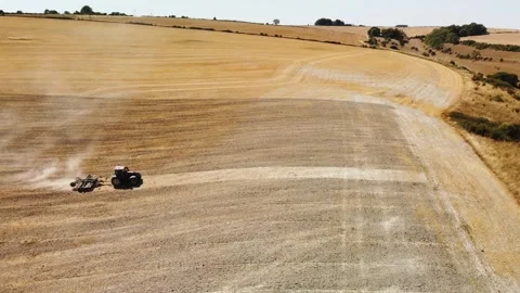 A tractor rolls a drought ridden dusty field in Wiltshire. Left to right Stock Footage 341993229