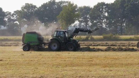 Tractor runs on the field in the fall and gathers hay in bales Stock Footage 84413473