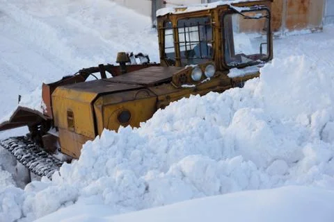 Tractor with scraper removes snow Stock Photos