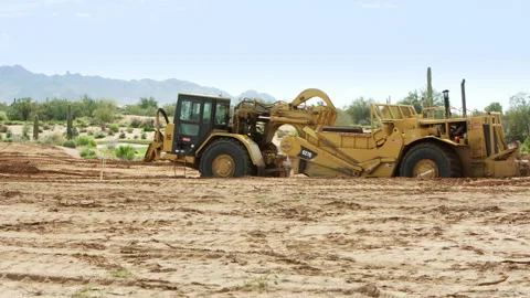 Tractor Scraper scraping dirt grading terrain for building houses. Stock Footage 217509997