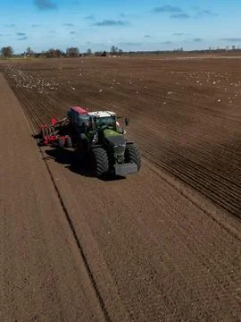 Tractor with seed drill forms straight furrows on open farmland Stock Photos