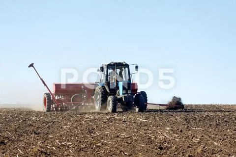 Tractor with a seeder on the field Stock Photos