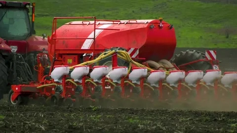 A tractor with a seeder rides through the field in the spring and sows wheat Stock Footage 239149764