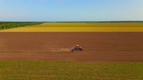 A tractor seeding crops in field next to fields of young corn and rapeseed Stock Footage 134507459