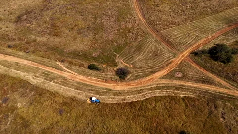 Tractor slashing thick grass next to dirt road before firebreak burn Stock Footage 312987101