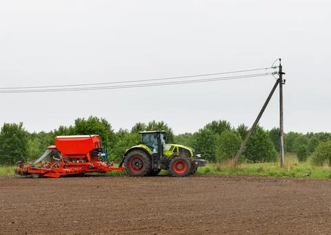 A tractor with a sowing complex processes agricultural land. Stock Photos