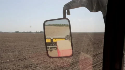 Tractor is sowing corn driving in the field. View in the rearview mirror of the  Stock Footage 223525216