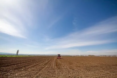 Tractor sowing of seed to field at spring time Stock Photos
